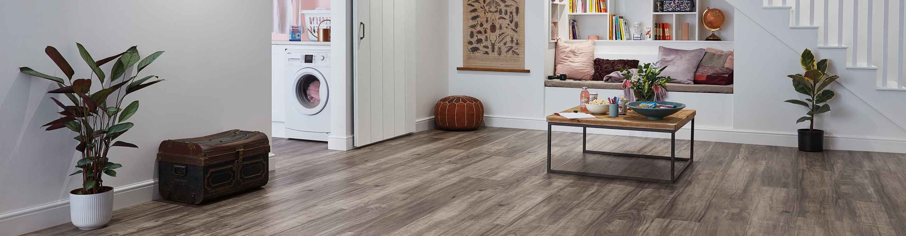 gray plank vinyl flooring in modern basement with reading nook, coffee table and sliding barn doors into laundry room